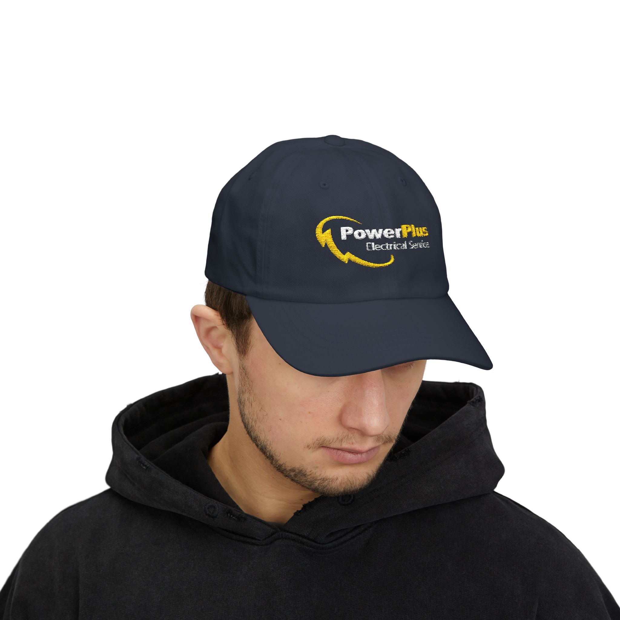 A man wearing a black hoodie and a navy Power Plus Electrical Services Embroidered Hat (Yupoong 6245CM) featuring the yellow and white logo looks down.
