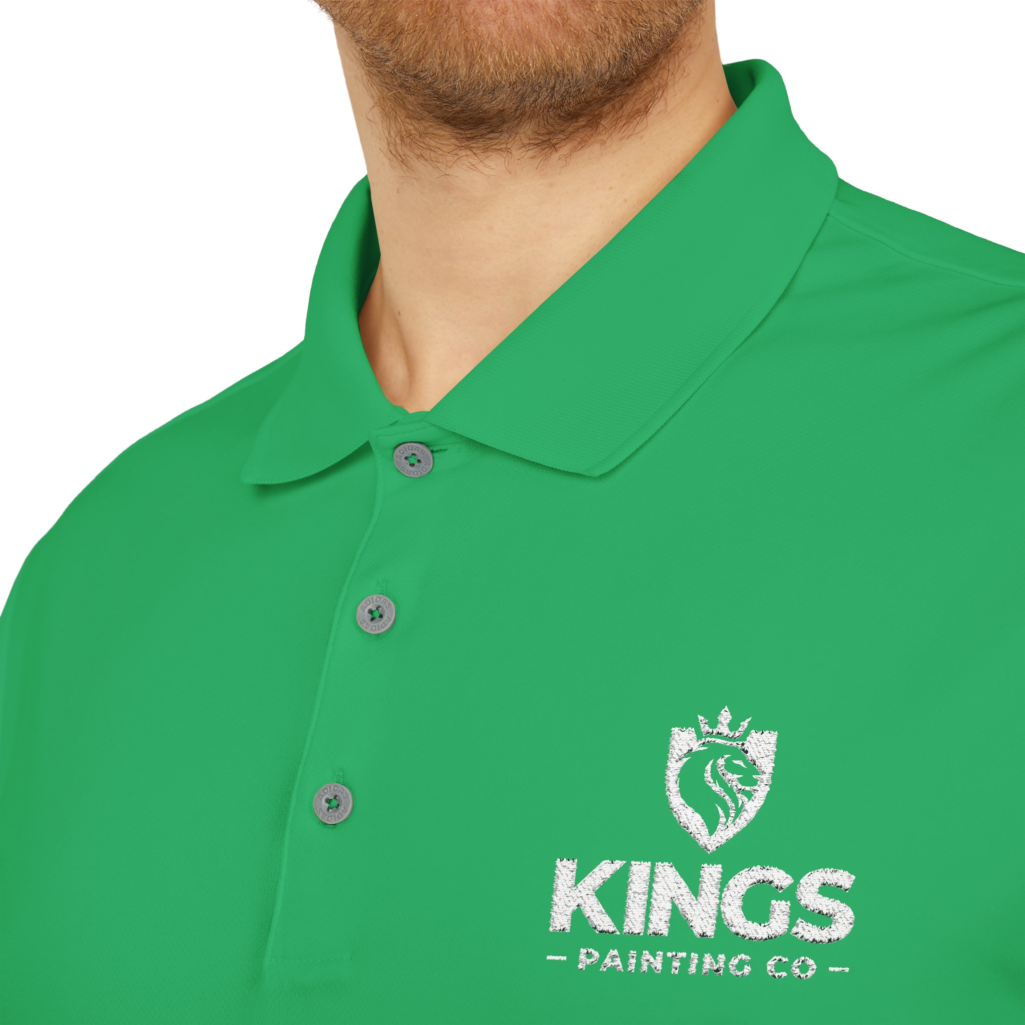 A person is shown wearing the Kings Painting Co. Performance Polo by Under Armour®, featuring a white embroidered logo with a lion and crown on the chest; only the lower half of their face and upper torso are visible.